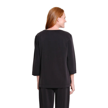 A woman with red hair is shown from the back wearing a black three-quarter sleeve top and matching black pants against a plain white background.