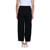 A model shown from the back wearing black wide-leg cropped pants, a white ribbed tank top, and white slip-on sneakers against a plain white background.