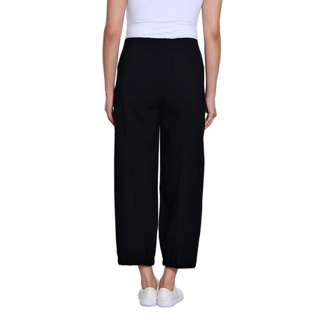 A model shown from the back wearing black wide-leg cropped pants, a white ribbed tank top, and white slip-on sneakers against a plain white background.