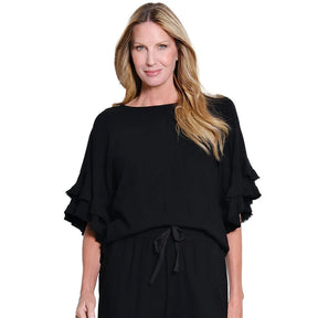 Woman wearing a black outfit with ruffled sleeves on a white background