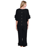 Woman wearing a black outfit with ruffled sleeves and pants on a white background