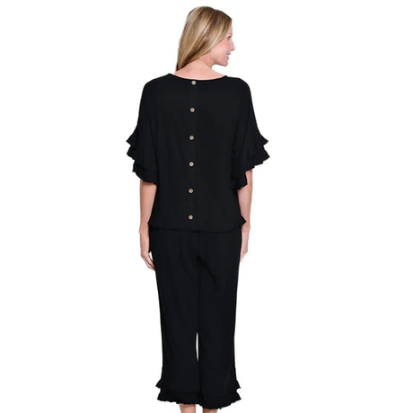 Woman wearing a black outfit with ruffled sleeves and pants on a white background