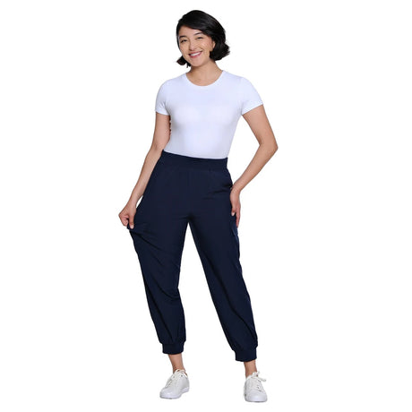 A woman modeling a white short-sleeve crewneck t-shirt and dark navy jogger pants with white sneakers, set against a solid white background.
