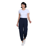 A woman modeling a white short-sleeve crewneck t-shirt and dark navy blue jogger pants with white sneakers, set against a solid white background.