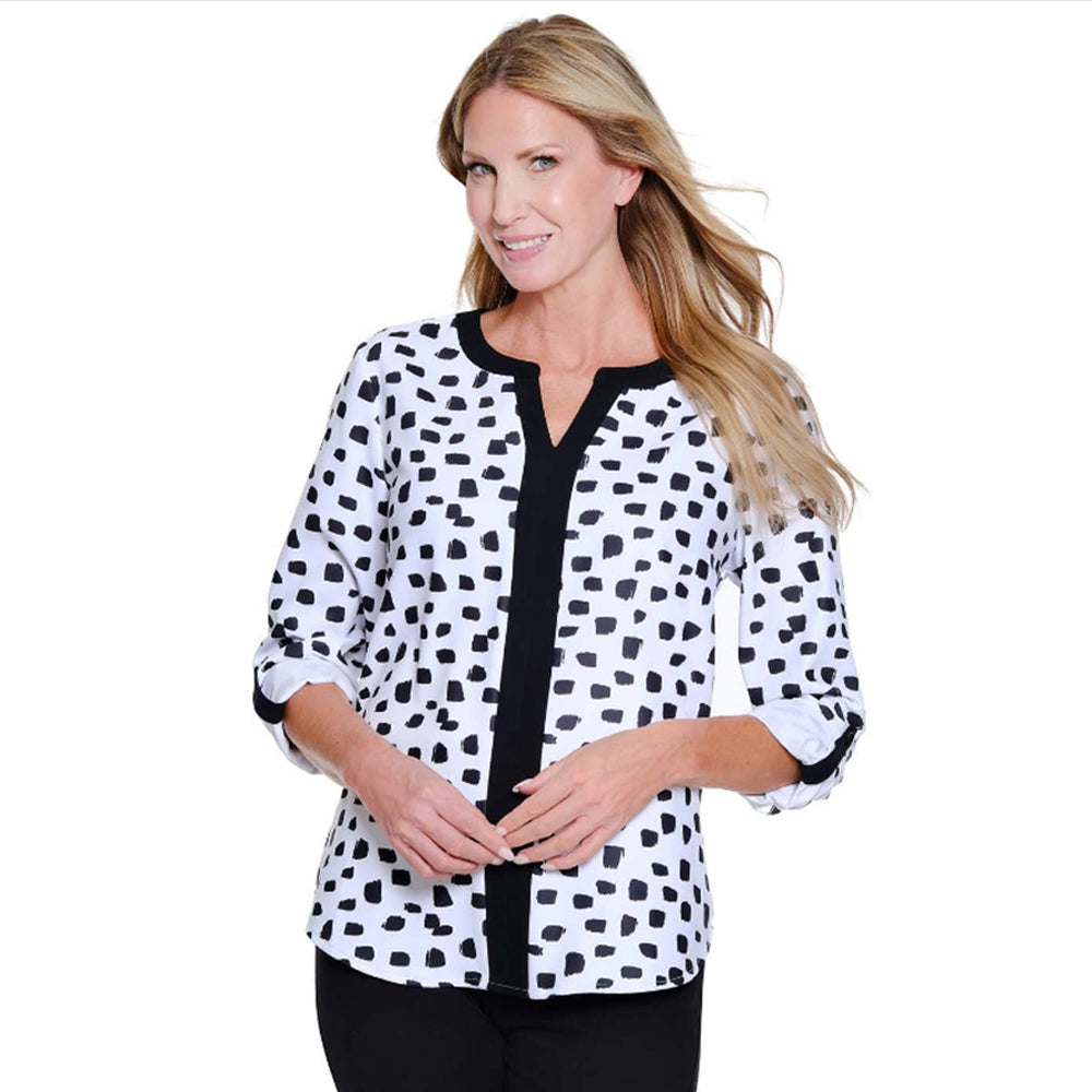 Woman wearing a black and white polka dot blouse with a black trim on a white background