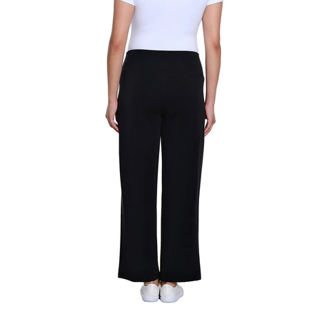 A model shown from the back wearing black wide-leg trousers, a white top, and white sneakers against a plain white background.