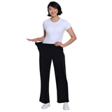 A woman modeling black wide-leg pants, holding the sides of her waist to demonstrate how loose or tight the fit is, paired with a white t-shirt and white sneakers against a plain white background.