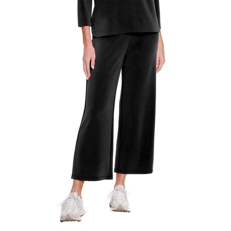 Person wearing black wide-leg pants and white sneakers on a white background
