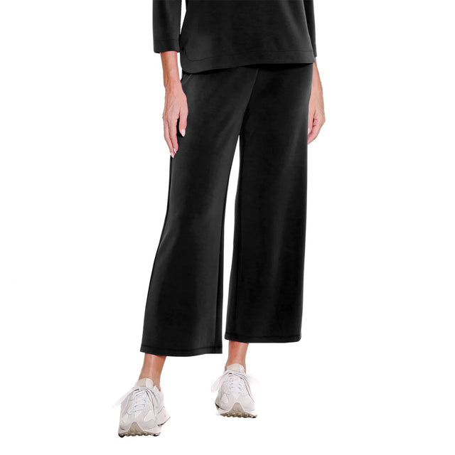 Person wearing black wide-leg pants and white sneakers on a white background