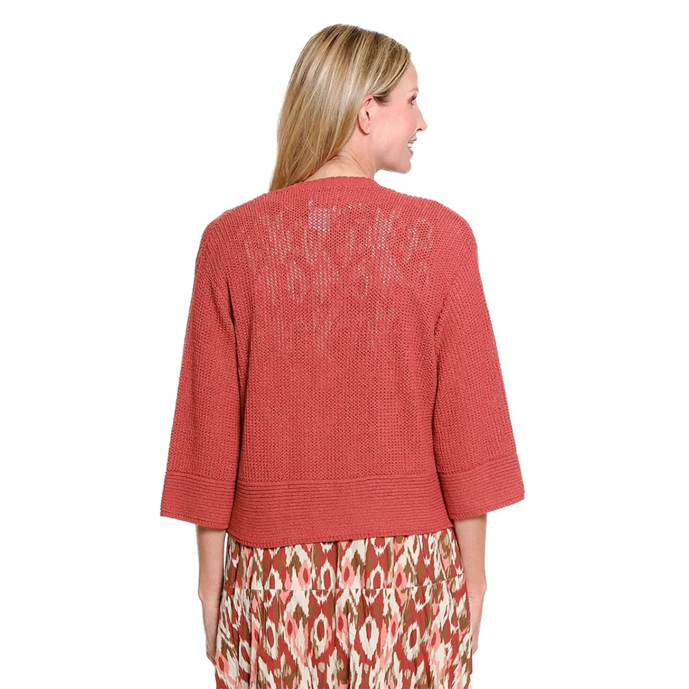 A woman modeling a rust-colored knit cardigan over a patterned midi dress with a matching headband, paired with strappy high-heeled sandals, against a plain white background.