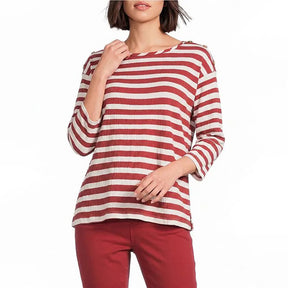 A woman wearing a red and off-white horizontally striped long-sleeve top with red pants, shown from the lips down against a plain white background.