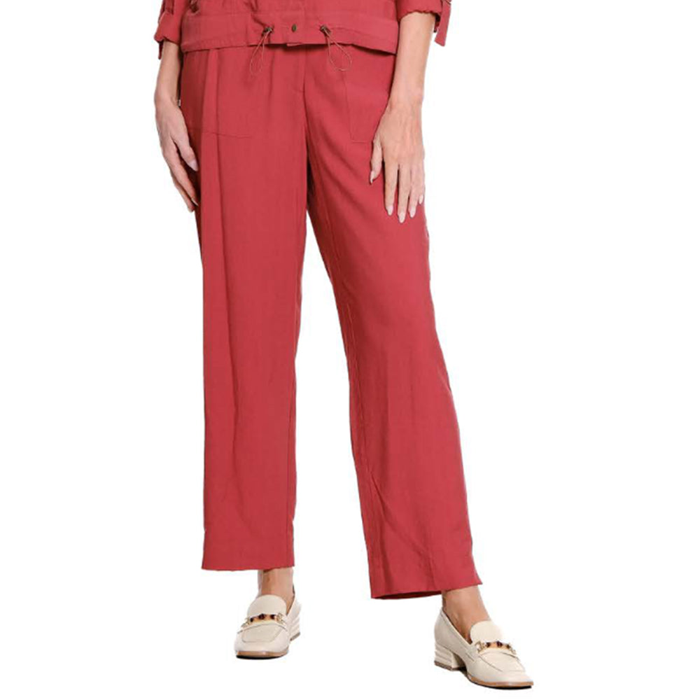 A model is wearing a pair of wide-leg cropped trousers in a dusty rose red color, paired with a matching top and cream-colored loafers, shown against a plain white background.
