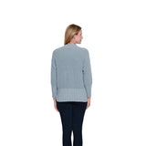 Woman wearing a light blue sweater with a textured pattern on a white background