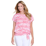 Woman wearing a pink and white zigzag patterned top on a white background