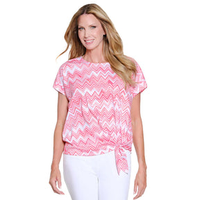 Woman wearing a pink and white zigzag patterned top on a white background