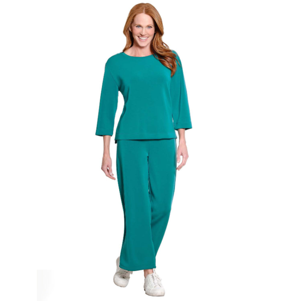 A woman modeling a matching teal two-piece lounge set consisting of a three-quarter sleeve top and wide-leg pants, paired with white sneakers, against a plain white background.