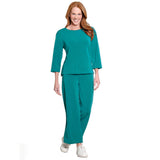 A woman modeling a matching teal two-piece lounge set consisting of a three-quarter sleeve top and wide-leg pants, paired with white sneakers, against a plain white background.