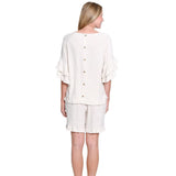Woman wearing a white outfit with a top and shorts on a white background