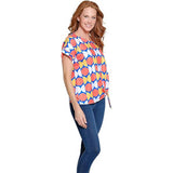 Woman wearing a colorful patterned top and blue jeans on a white background