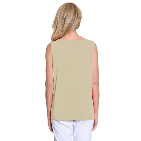 Woman wearing a beige sleeveless top and white pants on a white background