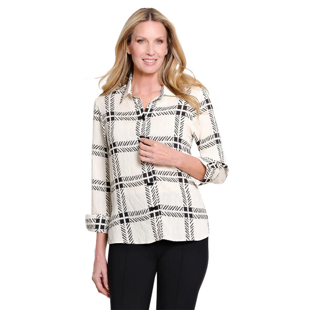 A woman modeling a long-sleeve button-up blouse with a black and off-white plaid pattern, paired with black pants, against a plain white background.