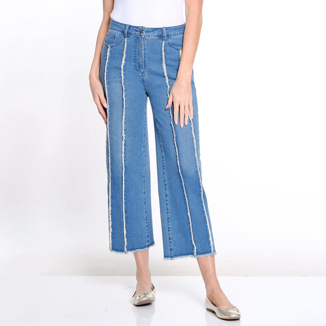 Person wearing blue jeans with white stripes on a white background