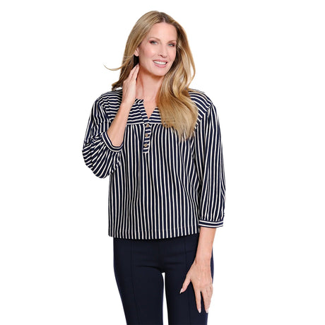 A woman modeling a navy and white vertically striped long-sleeve blouse with a buttoned split neckline, paired with dark pants, against a plain white background.