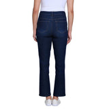 Rear view of a person wearing dark blue flare jeans with a white top and white sneakers against a plain white background.
