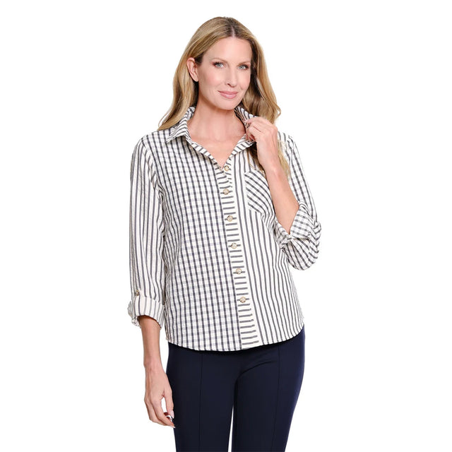 A woman modeling a long-sleeve button-up shirt with a black and white gingham pattern, paired with dark navy pants, against a solid white background.