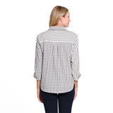 A woman viewed from the back wearing a white button-up shirt with black vertical and small check stripes, paired with dark navy pants, against a plain white background.