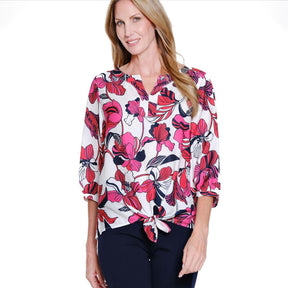 Woman wearing a floral blouse with pink and black flowers on a white background