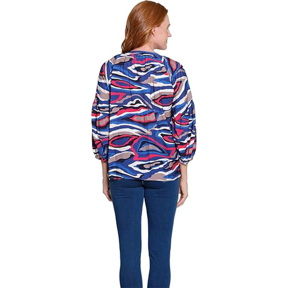 Woman wearing a colorful patterned shirt and blue pants on a white background