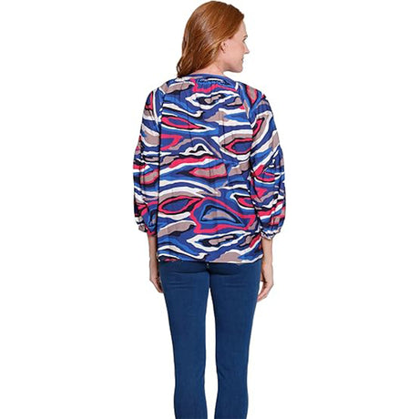 Woman wearing a colorful patterned shirt and blue pants on a white background