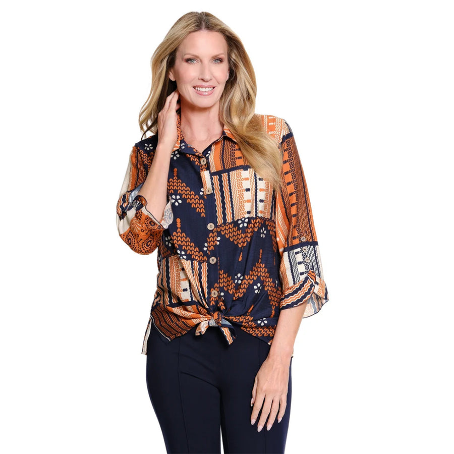 A woman modeling a patterned button-up blouse with three-quarter sleeves and a tied waist, paired with dark pants, against a plain white background.