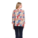 A woman viewed from the back wearing a long-sleeve blouse with a multicolor geometric patchwork pattern in red, blue, beige, and white, paired with dark navy pants, against a plain white background.