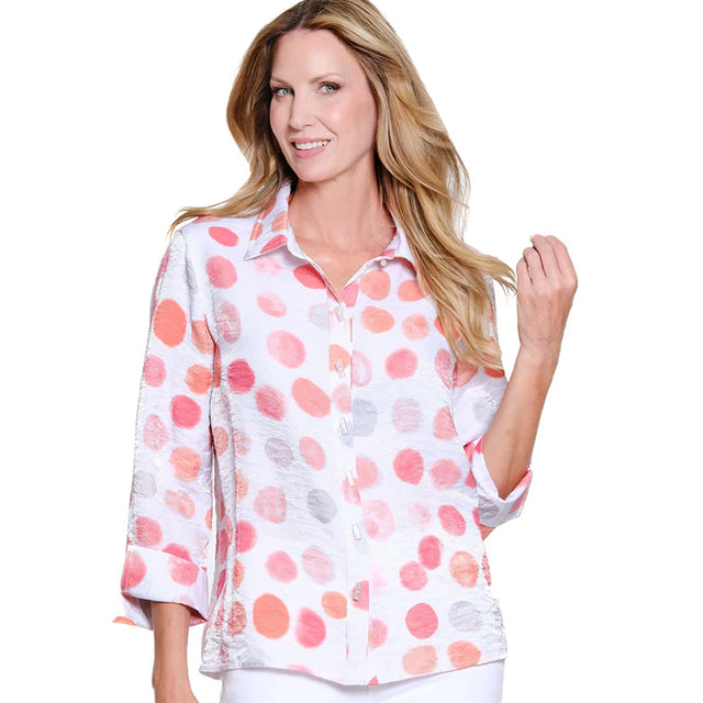 Woman wearing a white blouse with pink and orange polka dot pattern on a white background