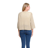 A woman modeling a textured, open-front cardigan in a light beige color, worn over a cream top and blue jeans, against a plain white background.