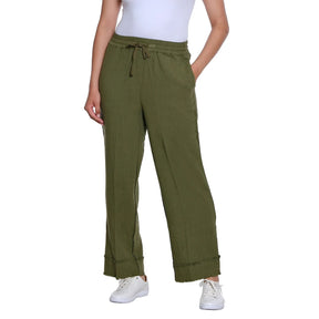 A person wearing olive green wide-leg drawstring pants with a white top and white sneakers, shown against a plain white studio background.