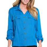 A woman wearing a bright blue button-up shirt with two chest pockets, frayed pocket edges, and brown buttons, shown against a plain white background.