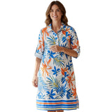 Woman wearing a colorful dress with a floral pattern in a clothing store.