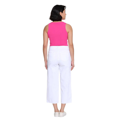 Woman wearing a pink sleeveless top and white pants on a white background