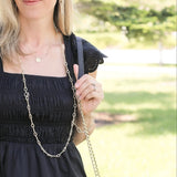 Woman wearing a black dress with a gold chain necklace outdoors