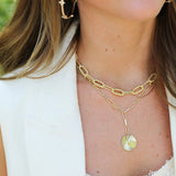 Close-up of a person wearing gold necklaces and earrings with a blurred background