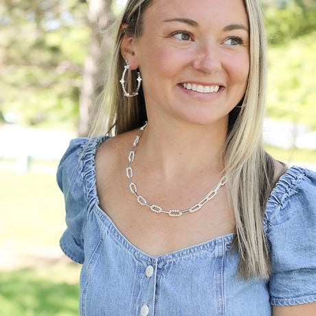 Woman wearing a silver necklace and hoop earrings outdoors