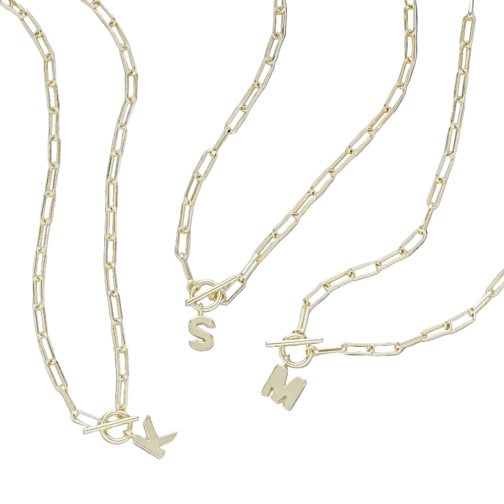 Three gold chain necklaces with charms on a light gray background