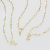 Three gold chain necklaces with charms on a light gray background