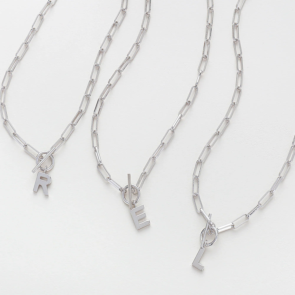 Three silver chain necklaces with letter pendants on a white background