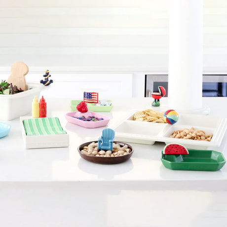 Colorful snack trays and bowls on a white surface with decorative items.
