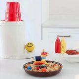Bowl of dog treats with a toy horse, red cups, and condiment bottles on a white surface.