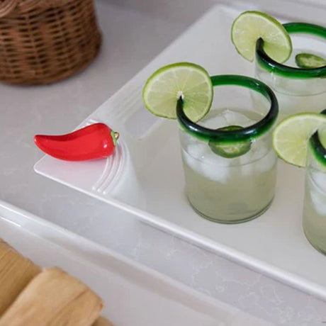 Three glasses of lime-wrapped margaritas on a white tray with a red pepper garnish.